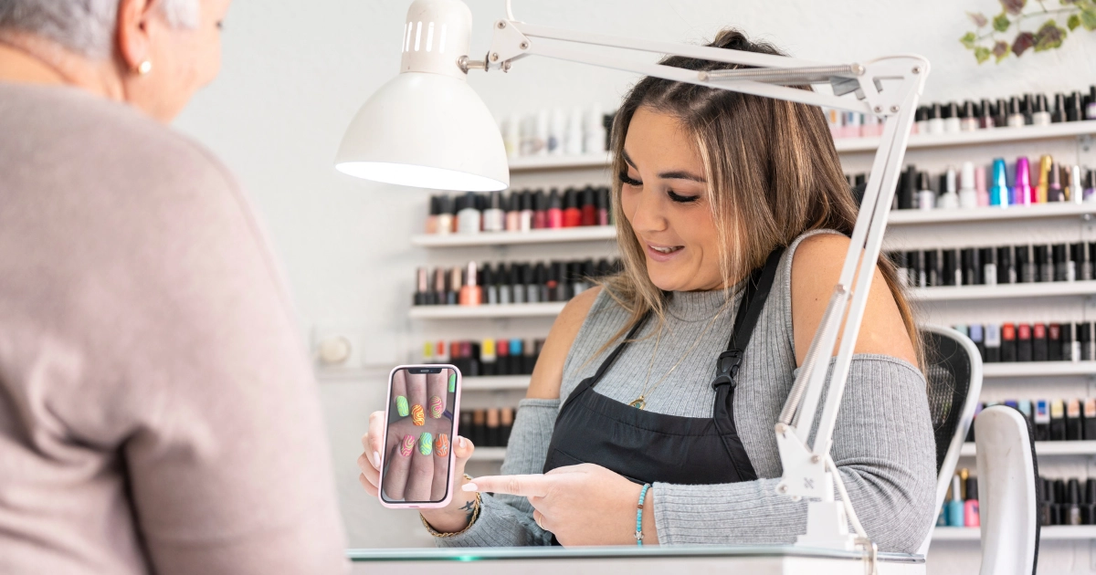 Nail technician discussing a manicure inspiration photo with a client